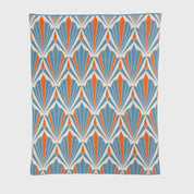 The In2Green Art Deco Shells Throw Blanket features a repeating geometric pattern of stylized shell shapes in blue, orange, and white, arranged in rows for a bold and modern look.