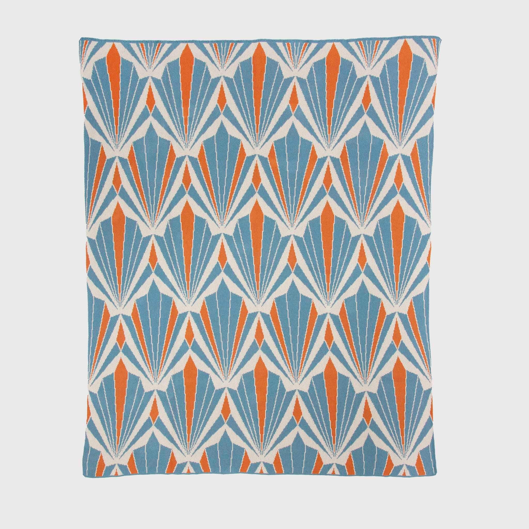 The In2Green Art Deco Shells Throw Blanket features a repeating geometric pattern of stylized shell shapes in blue, orange, and white, arranged in rows for a bold and modern look.