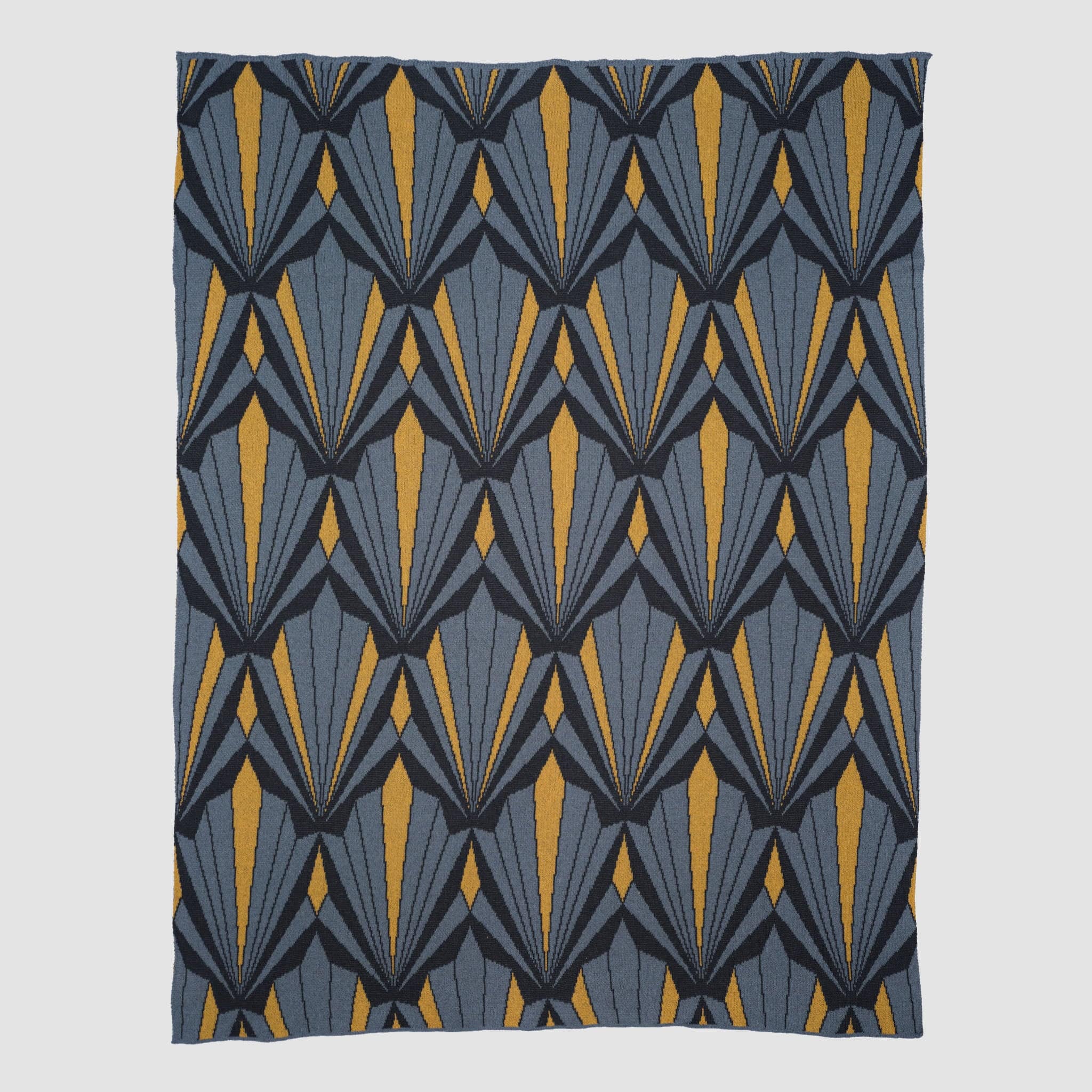 The In2Green Art Deco Shells Throw Blanket is a rectangular luxury throw with a repeating geometric Art Deco pattern in blue, grey, and yellow.
