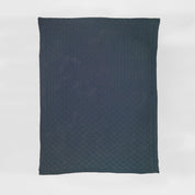 A navy rectangular Basketweave Throw Blanket by in2green, made from recycled yarns and featuring a subtle check pattern, is shown against a white background for an eco-friendly accent.