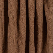 Close-up of the in2green Basketweave Throw Blanket, made from sustainable recycled yarns with brown knitted fabric, vertical folds, and textured intersecting lines.