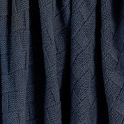 The Basketweave Throw Blanket by in2green features a dark blue, textured geometric pattern of interlocking rectangles and diagonal lines, crafted from sustainable recycled yarns for an eco-friendly touch.