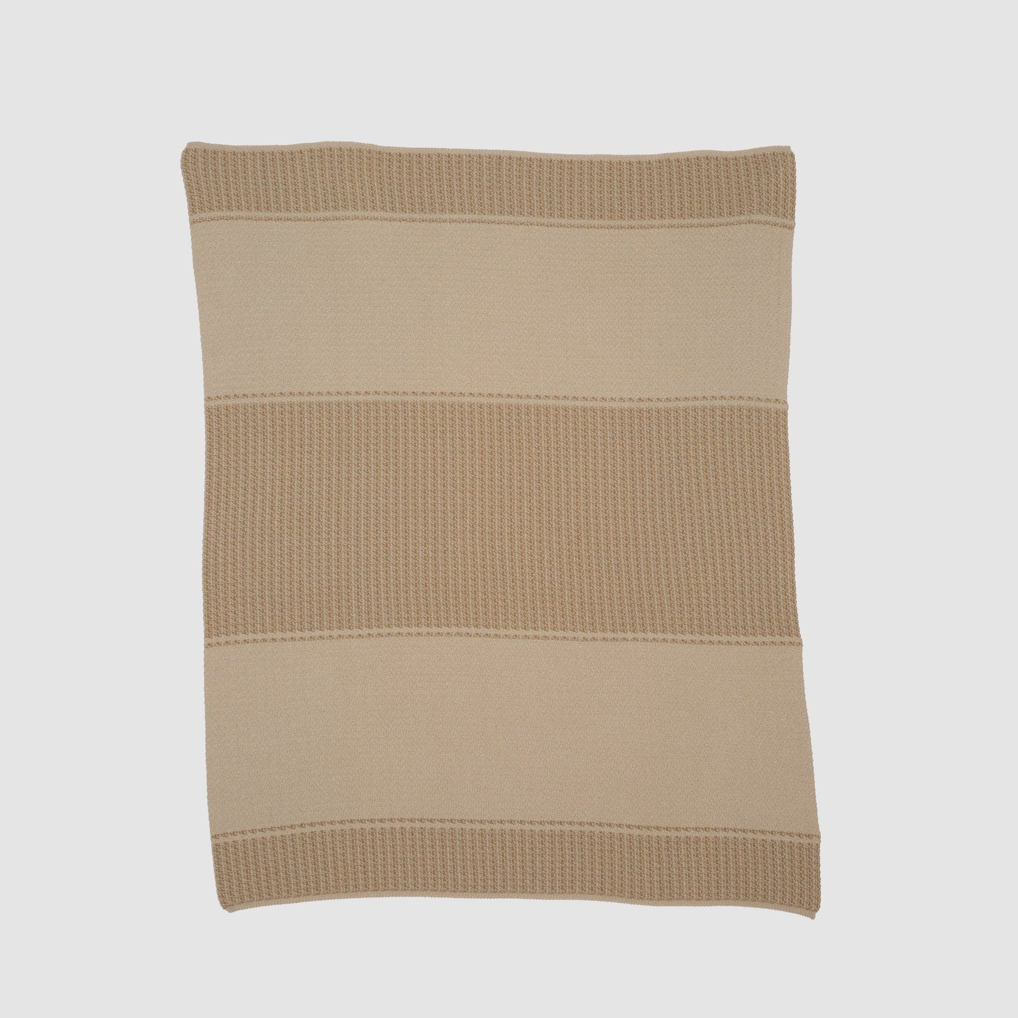 The Block Canyon Throw Blanket, shown on a plain white background, is crafted from sustainable recycled yarns and features alternating bands of textured and smooth patterns in a square beige knit design.