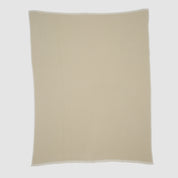The Checkerboard Throw Blanket is a beige, rectangular knit with a subtle textured pattern and white trim, crafted from sustainable upcycled cotton—perfect for adding cozy style to any space. Shown flat on a plain white background.