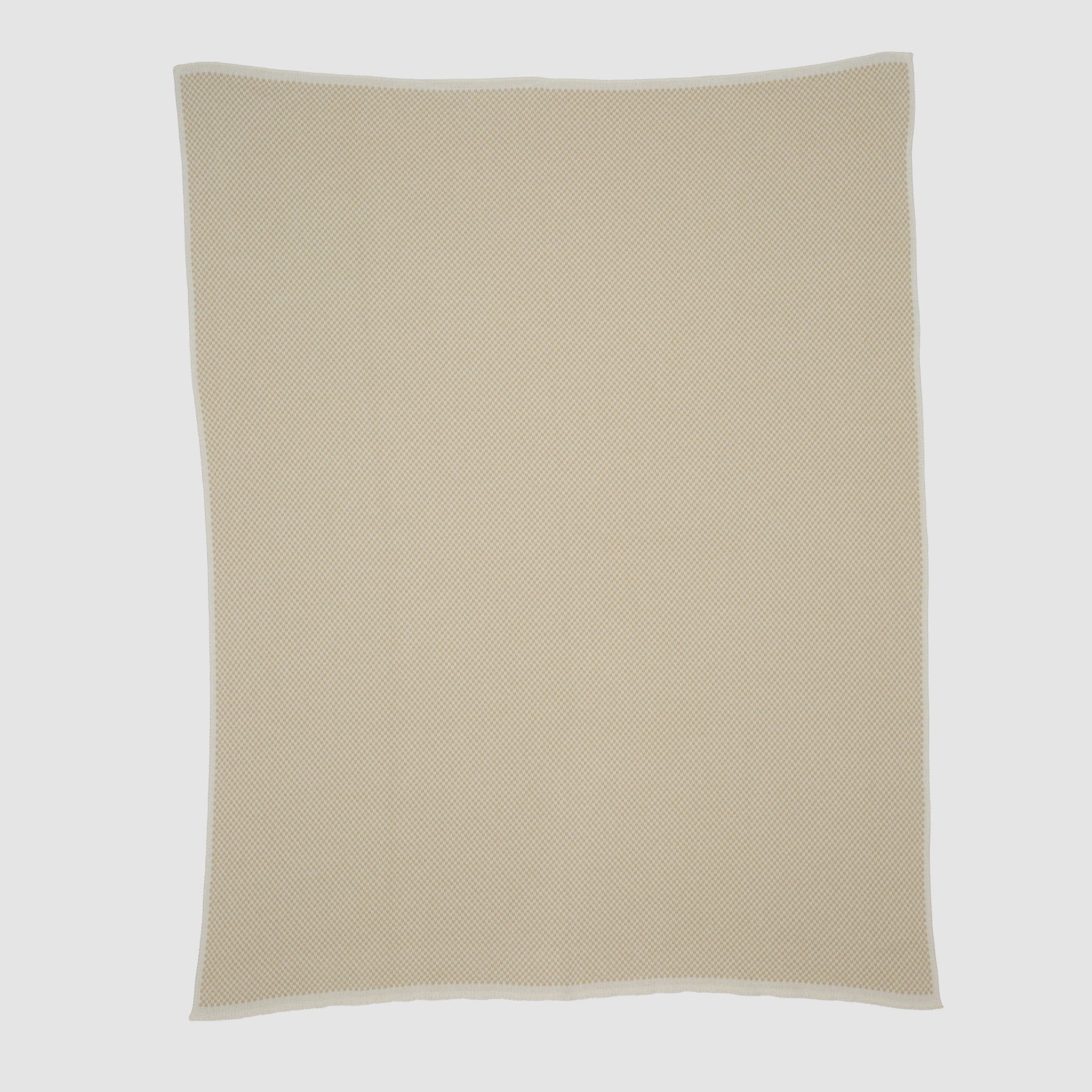 The Checkerboard Throw Blanket is a beige, rectangular knit with a subtle textured pattern and white trim, crafted from sustainable upcycled cotton—perfect for adding cozy style to any space. Shown flat on a plain white background.
