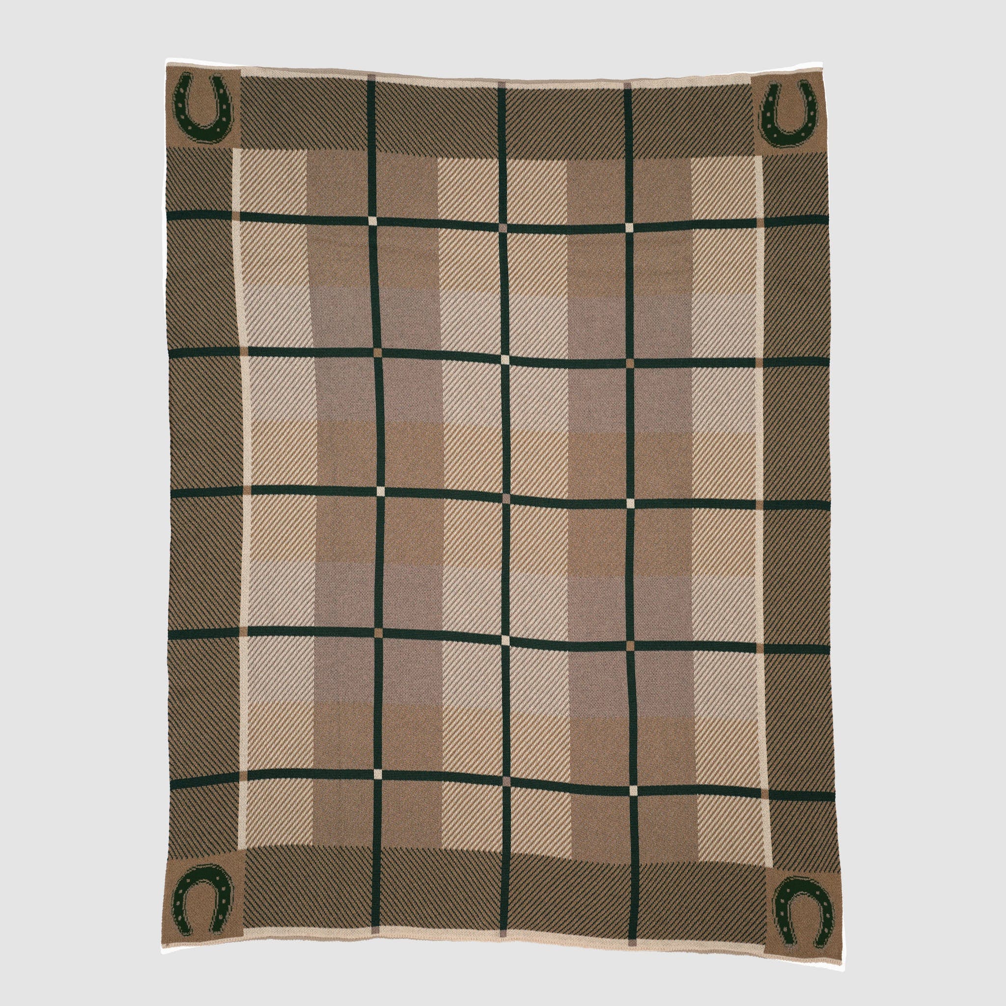 The In2Green Equestrian Barn Plaid Throw Blanket features a rectangular design in brown, tan, and beige with green horseshoe motifs in each corner. Made from recycled polyester for a cozy, eco-friendly touch against a plain light background.