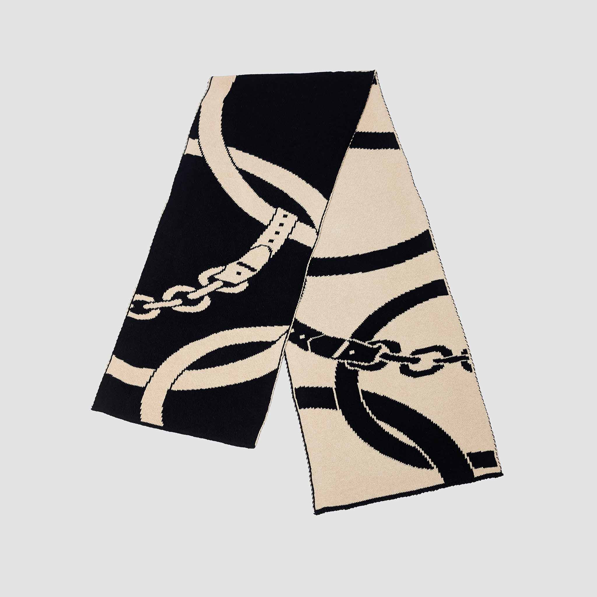 The Equestrian Loops Scarf by in2green is a long, rectangular sustainable cotton scarf with a black and beige abstract chain pattern on a plain background.
