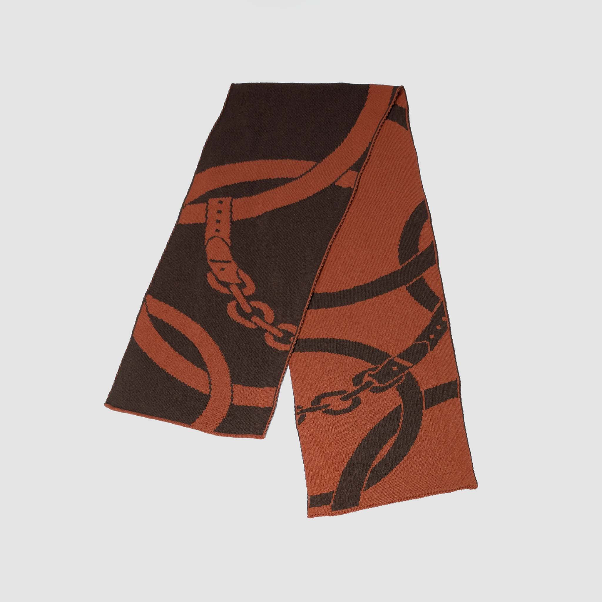 The Equestrian Loops Scarf by in2green features a bold, abstract chain and buckle pattern in brown and burnt orange—an eye-catching horse riding accessory.