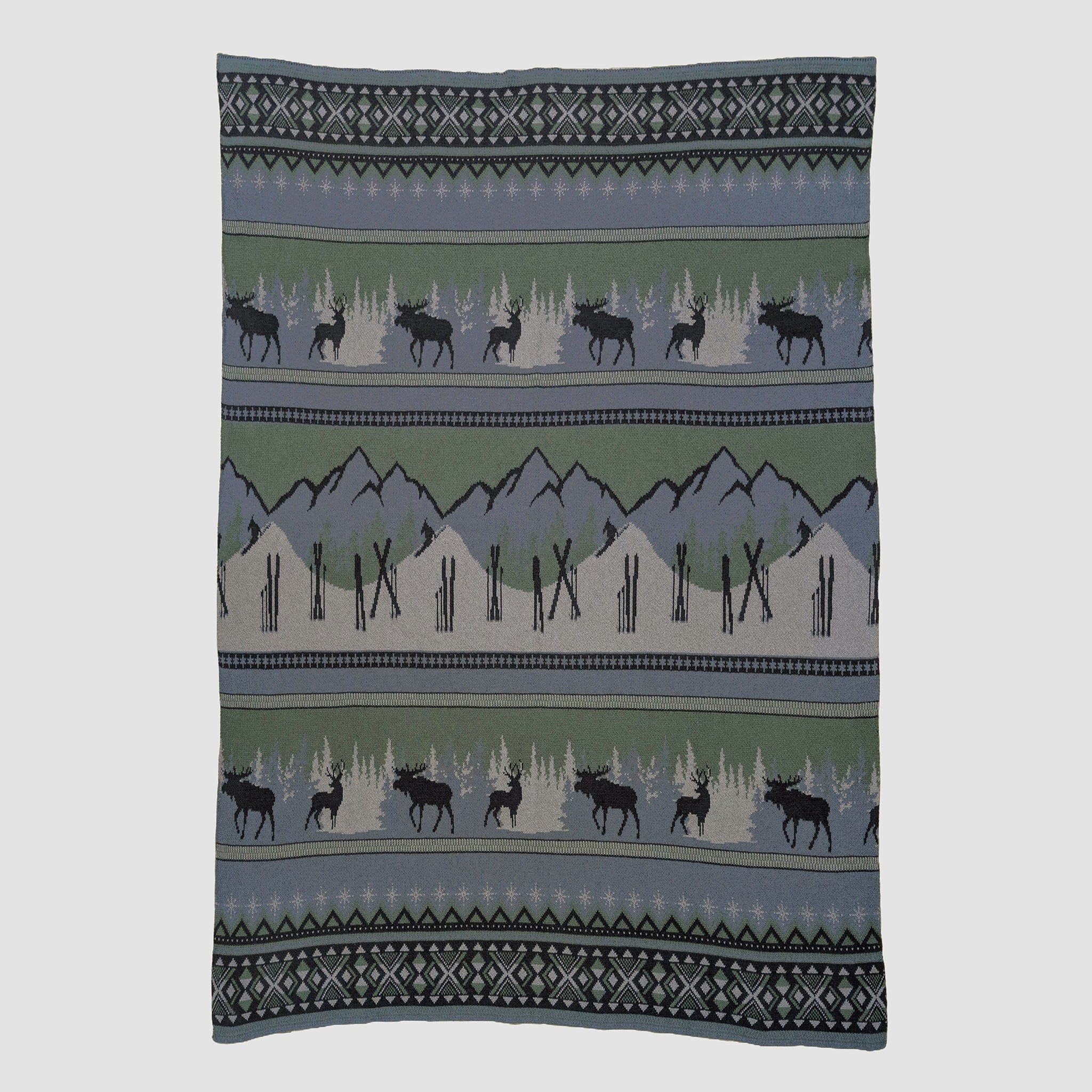 The in2green Mountain Fair Isle Throw Blanket features mountains, trees, and moose silhouettes in green, gray, black, and blue—crafted from recycled cotton for cozy holiday décor.