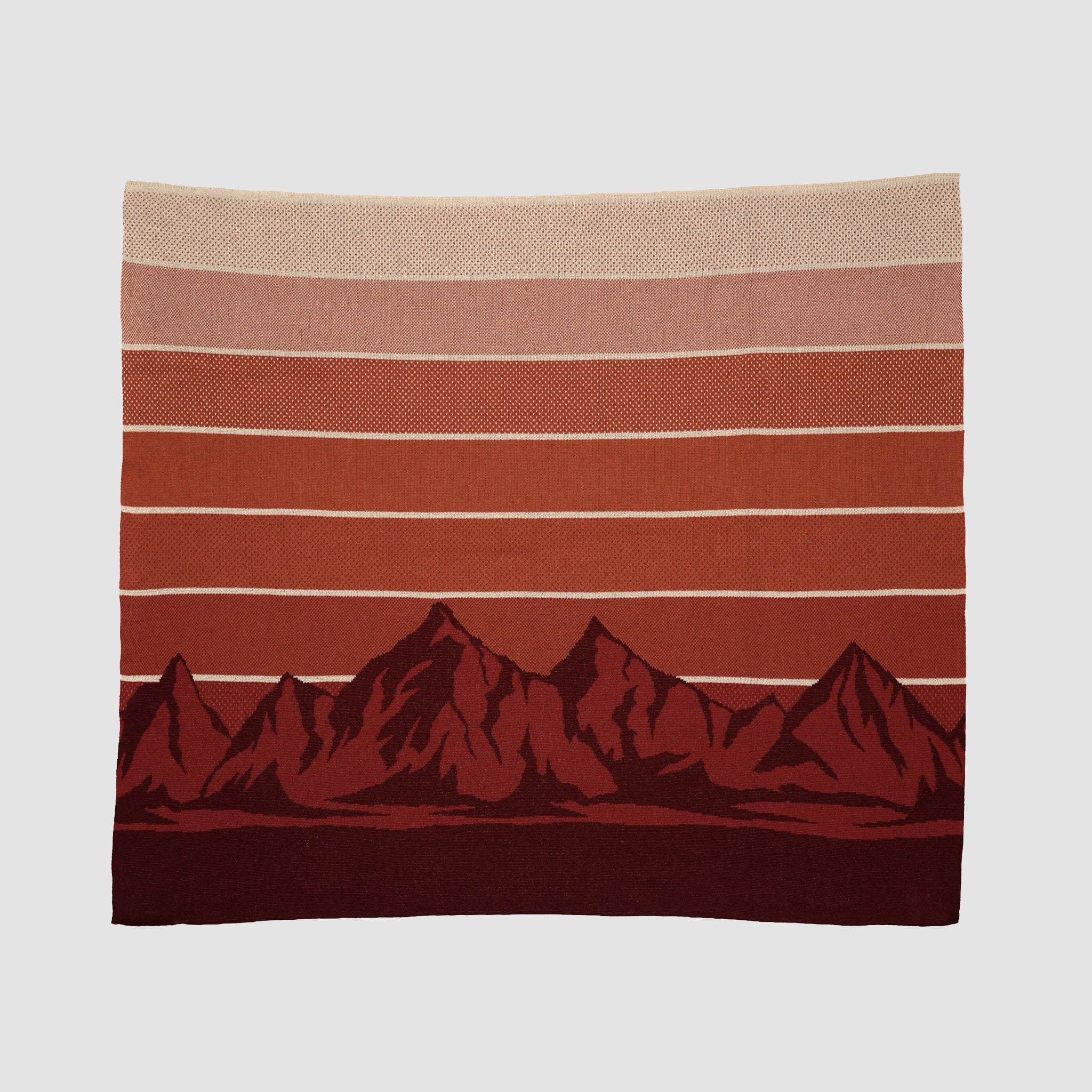 The Mountain Sunscape Throw Blanket is an eco-friendly blanket made from recycled cotton, featuring horizontal red and beige stripes and a mountain range design at the bottom for sustainable comfort.