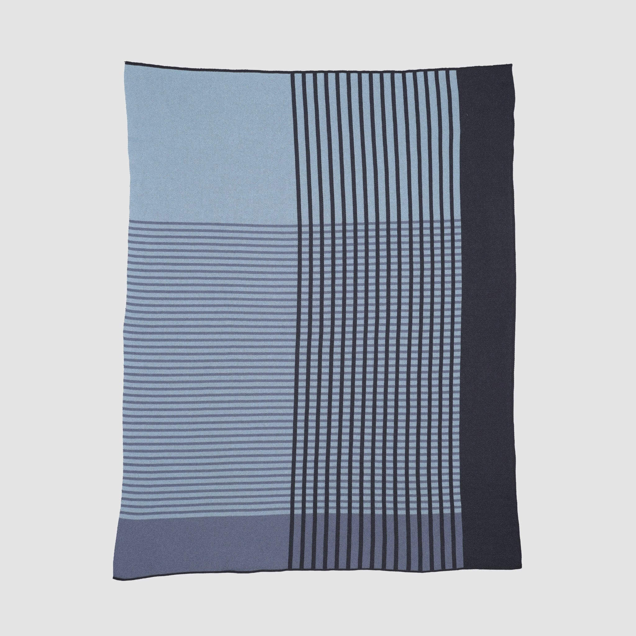 The Overlap Blanket by Kelly Harris Smith is a rectangular throw featuring a geometric pattern of horizontal and vertical lines in varying shades of blue and black. No additional product description is available.