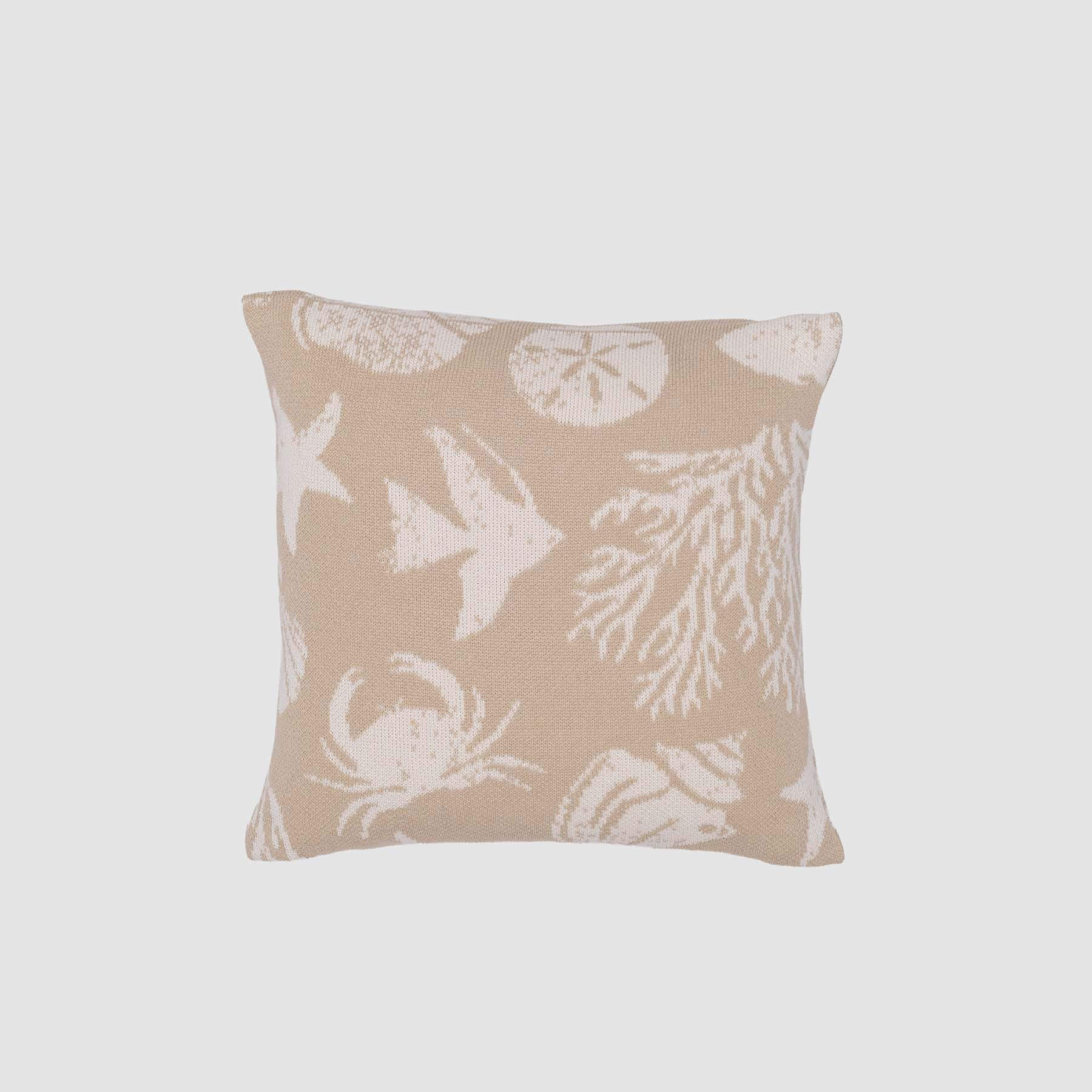 The in2green Sea Life Pillow is a square beige accent featuring white crab, coral, fish, starfish, and sand dollar designs—an eco-friendly touch for coastal decor. Set on a plain light background.