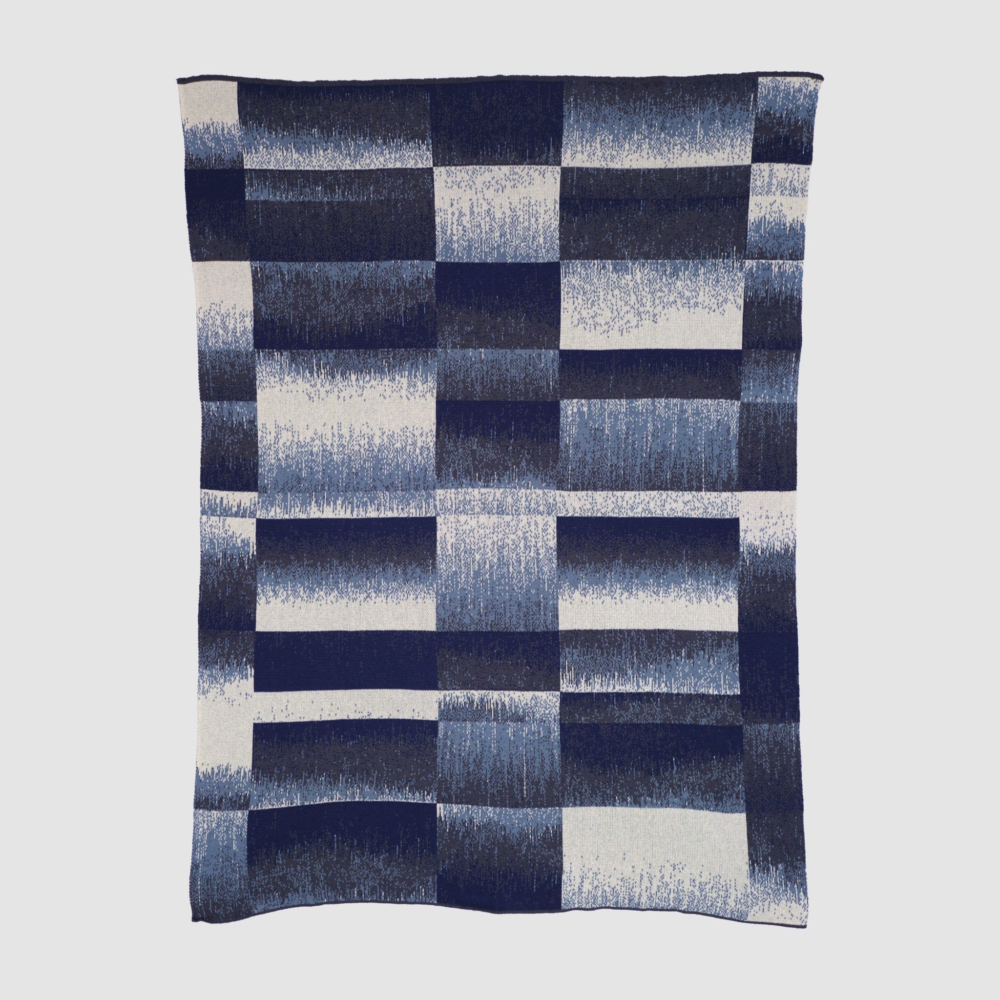 The Plaid Ombre Throw Blanket features a classic navy blue and white check with gradient squares, crafted from recycled yarn for a stylish, sustainable touch.