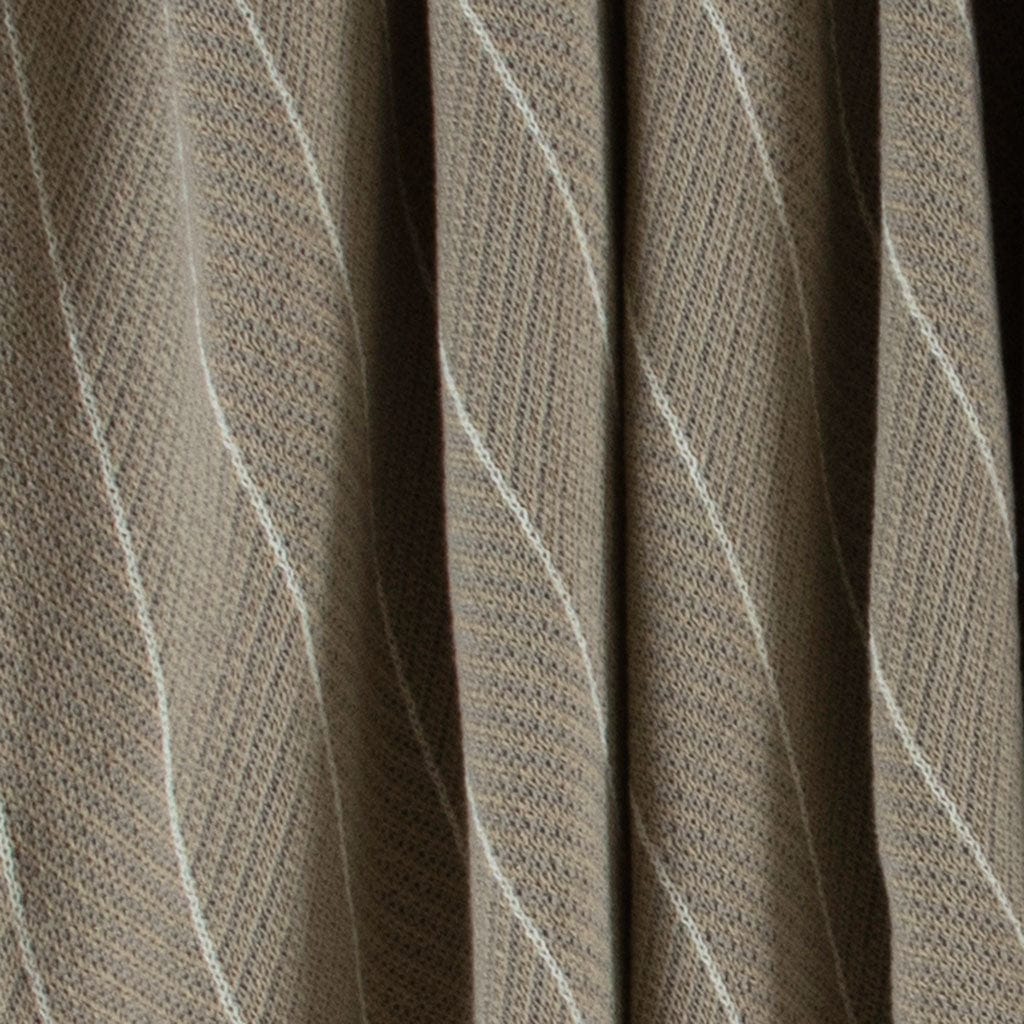 Close-up of the Poly Herringbone Edge Throw Blanket by in2green, showcasing its beige recycled polyester fabric with a distinct herringbone knit pattern in light and dark tones. The texture and weave are clearly visible.