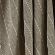 Close-up of the Poly Herringbone Edge Throw Blanket by in2green, showcasing its beige recycled polyester fabric with a distinct herringbone knit pattern in light and dark tones. The texture and weave are clearly visible.
