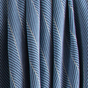 Close-up of the Poly Herringbone Edge Throw Blanket by in2green, showing blue and white recycled polyester knit with vertical folds.