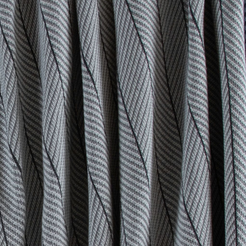 Close-up of the in2green Poly Herringbone Edge Throw Blanket, featuring gray herringbone knit with diagonal black lines and folds—ideal for outdoor use.