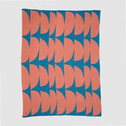 The Poly Kaareva Throw Blanket by Petra Kaksonen features repeating pink semicircles on a blue background, crafted from recycled polyester and part of her outdoor collection, shown on a plain surface.