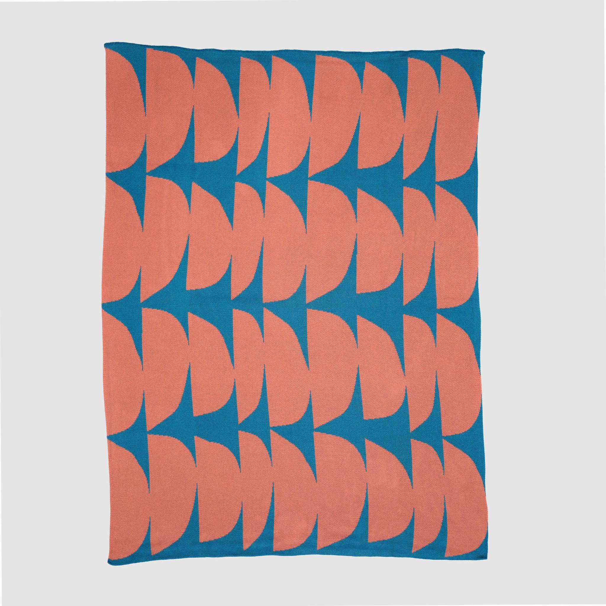 The Poly Kaareva Throw Blanket by Petra Kaksonen features repeating pink semicircles on a blue background, crafted from recycled polyester and part of her outdoor collection, shown on a plain surface.