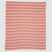The Poly Tikku Throw Blanket by Petra Kaksonen for in2green features rows of red and off-white triangles, bringing Scandinavian style to coastal decor. Made from recycled polyester, it's a modern and eco-friendly accent.