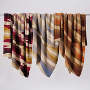 The in2green Southwest Arrows Throw Blankets, with earth-toned Southwestern-inspired patterns, hang side by side on a rod—bringing warmth and modern style to any home.