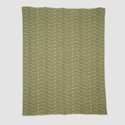 The Sand Stone Throw Blanket is a rectangular knit with earthy green and yellow stripes on a light background, made from eco-friendly yarns.