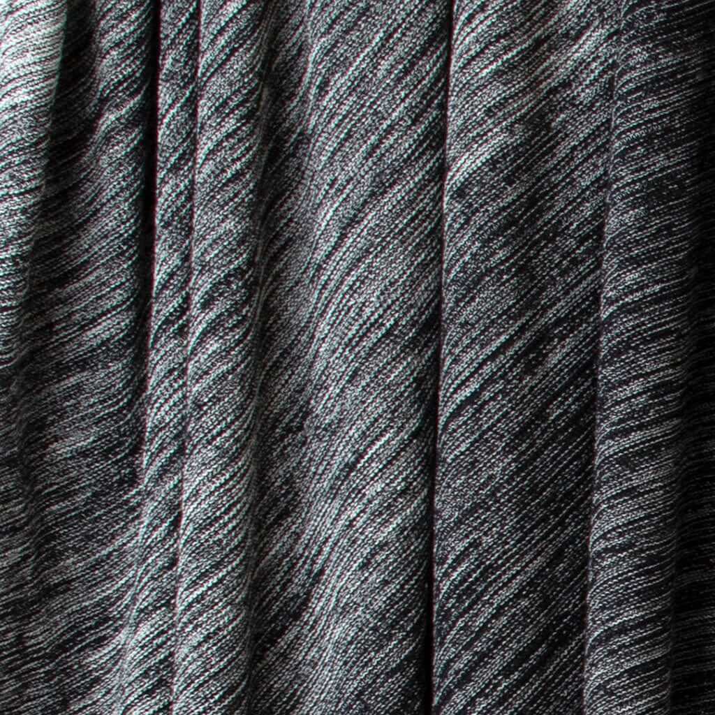 Close-up of the in2green Textured Ombre Throw Blanket, made from dark recycled cotton with a ribbed texture, diagonal lines, subtle shading variations, and draped in soft vertical folds.