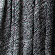 Close-up of the in2green Textured Ombre Throw Blanket, made from dark recycled cotton with a ribbed texture, diagonal lines, subtle shading variations, and draped in soft vertical folds.