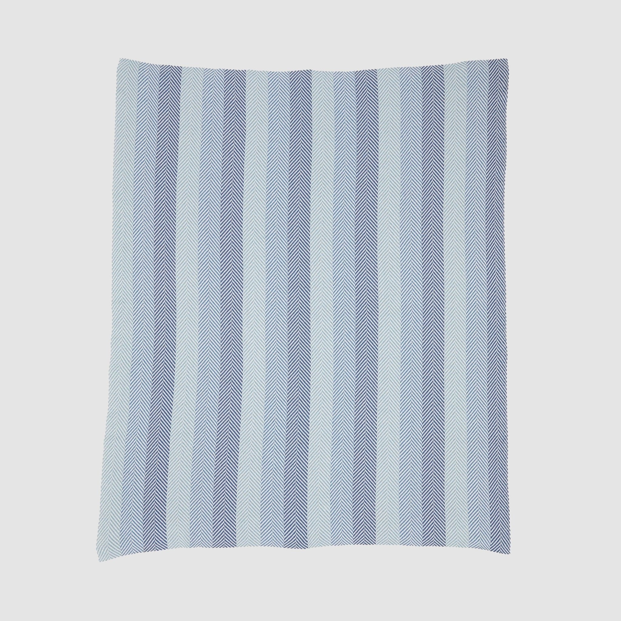 The Herringbone Hues Throw Blanket by In2Green is crafted in the USA from recycled cotton. Featuring alternating light and dark blue herringbone stripes on a white background, it combines style and sustainability for any setting.