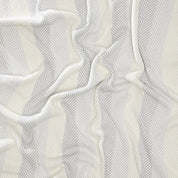 The Herringbone Hues Throw Blanket by In2Green is crafted in the USA from recycled cotton, featuring a wavy drape with a chevron pattern in alternating shades of cream and light gray.