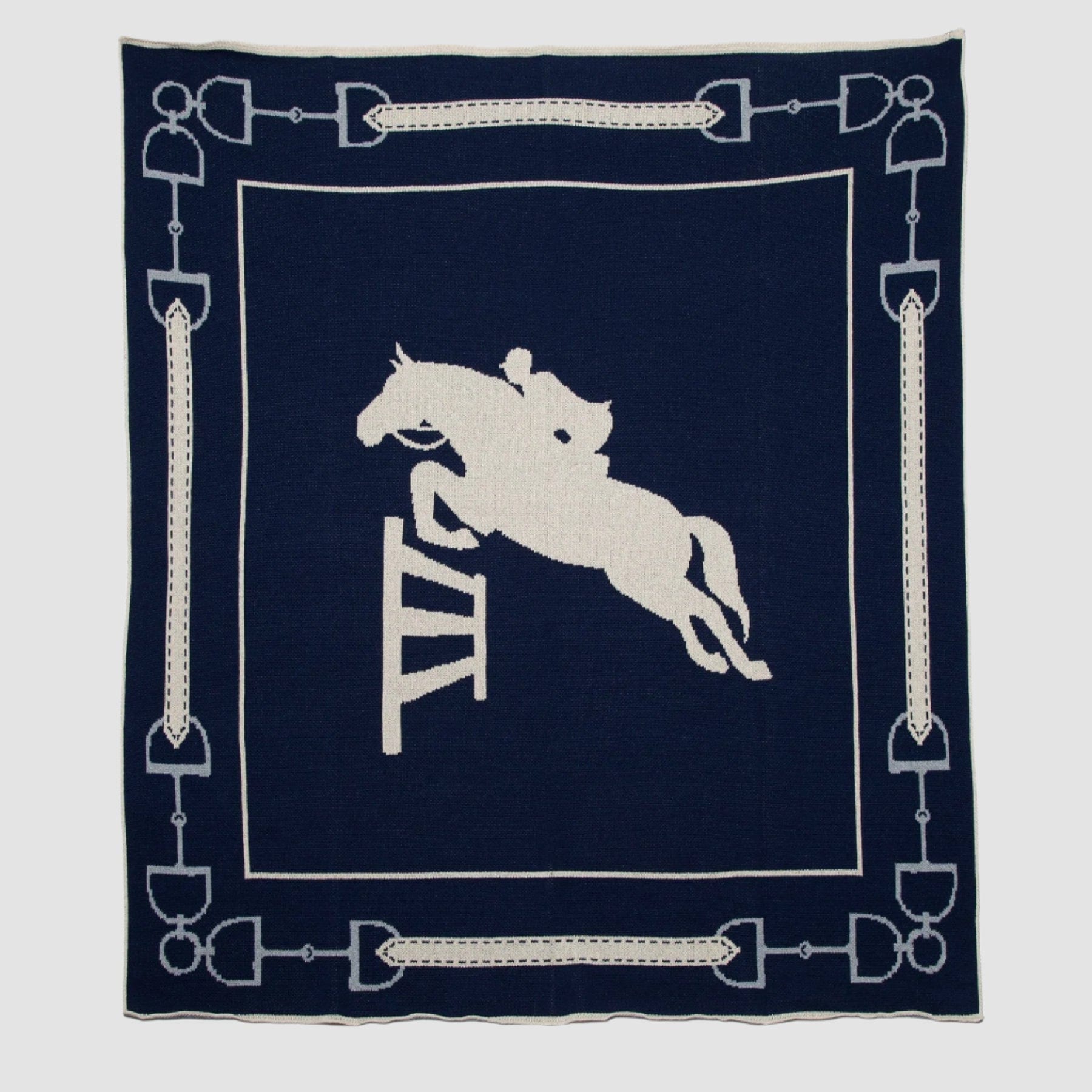 The in2green Equestrian Jumper Throw Blanket features a white silhouette of a horse and rider jumping over a hurdle, elegantly framed by horse bit designs.