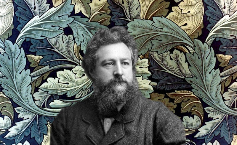 A bearded man in a suit poses elegantly against a vibrant backdrop, evoking the intricate botanical designs of the Arts and Crafts movement, similar to the Larkspur Throw Blanket by William Morris from in2green.