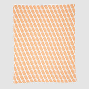 The Poly Juki Throw Blanket by Petra Kaksonen from in2green features an orange and white abstract pattern made from recycled polyester, displayed on a plain background.