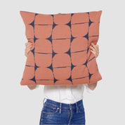 A person holds the Poly Kaarna Pillow by Petra Kaksonen, showcasing a stunning geometric Nordic design. The pillow features blue and rust circles on white, crafted from recycled polyester by in2green, blending sustainability with style.