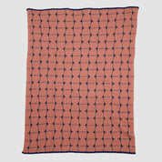 The Poly Kaarna Throw Blanket by Petra Kaksonen for in2green features a minimalist Scandinavian design with interconnected black shapes on a dusty rose background. Made from recycled polyester, it offers an eco-friendly touch.