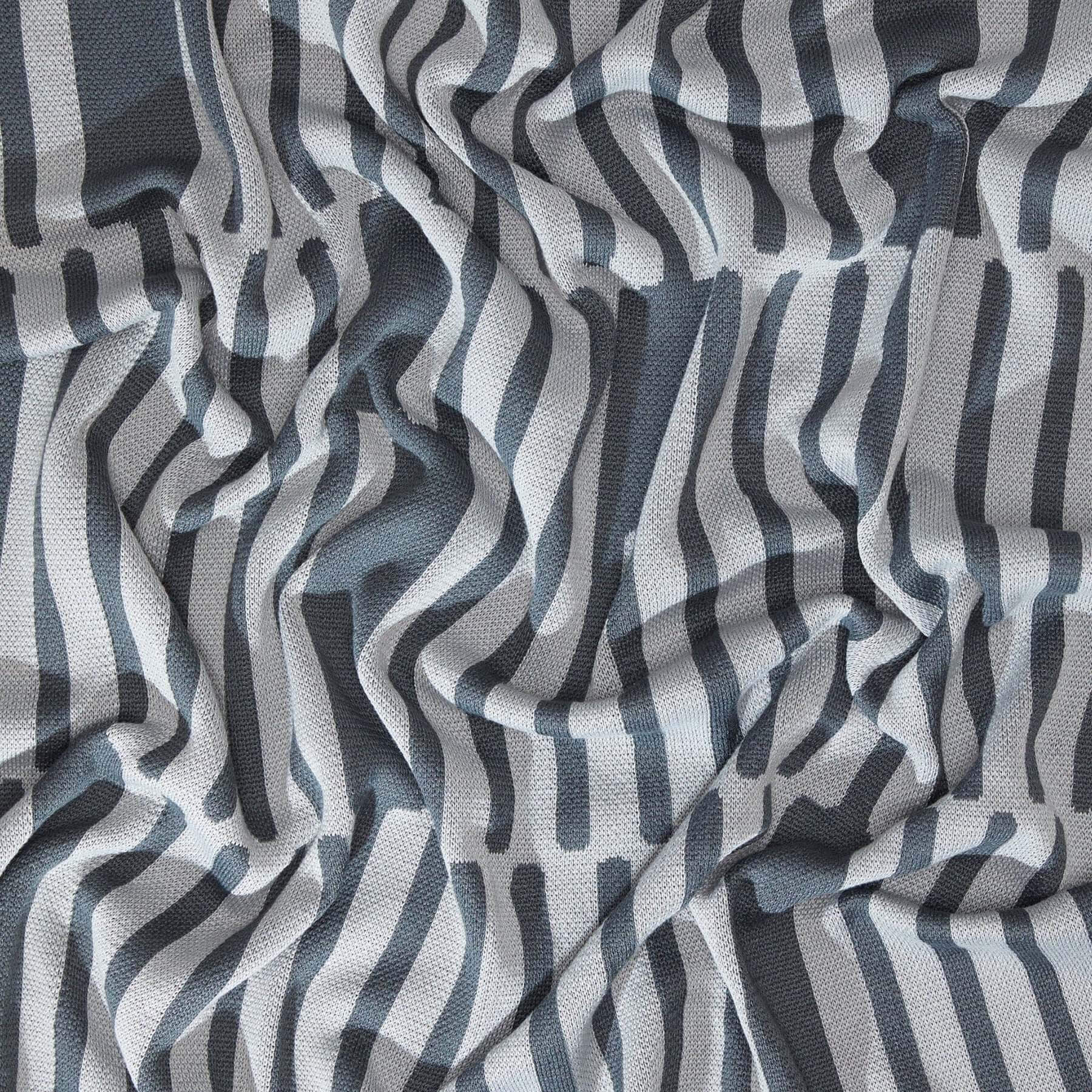 The Poly Retki Throw Blanket by Petra Kaksonen in charcoal and light grey.