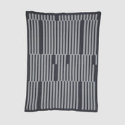 The Poly Retki Throw Blanket by Petra Kaksonen in charcoal and light grey