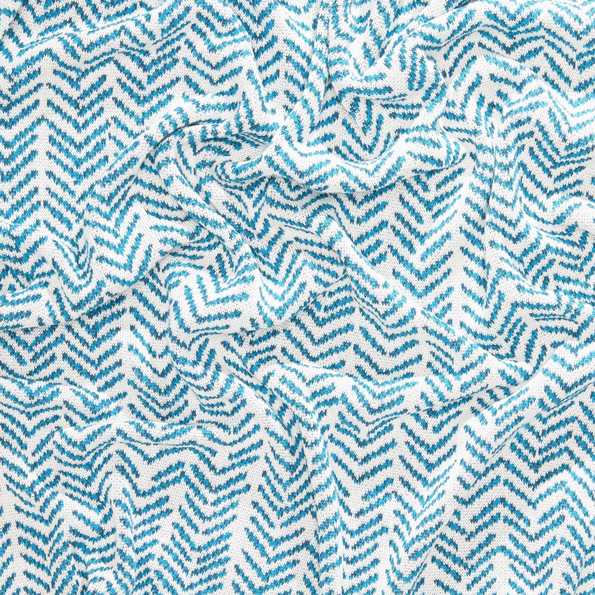 Close-up of a textured Warrior Throw Blanket Teal by In2Green, showcasing a teal and white zigzag pattern, offering comfort and unity to those in need of breast cancer support.