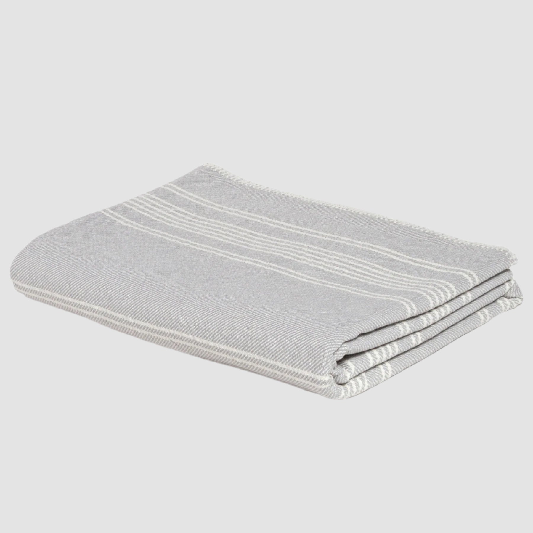 Introducing the Woven Twill Blanket by in2green, a folded gray throw crafted from recycled cotton and featuring elegant light stripe patterns.