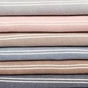 A collection of Woven Twill Blankets by in2green, featuring striped patterns in a range of colors such as gray, pink, beige, blue, and brown, crafted from eco yarns.