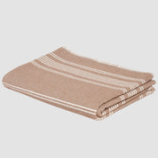 A folded Woven Twill Blanket by in2green, featuring a brown and white striped pattern and crafted from recycled cotton, rests against a pristine white background.