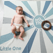 A baby lies on a Baby Milestone Personalized Blanket featuring an eco-friendly radial design with numbers for each month.