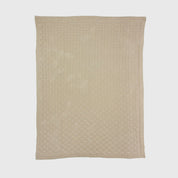 The in2green Basketweave Throw Blanket is a beige, rectangular throw with a subtle checkered pattern made from recycled yarns, shown flat on a white background.