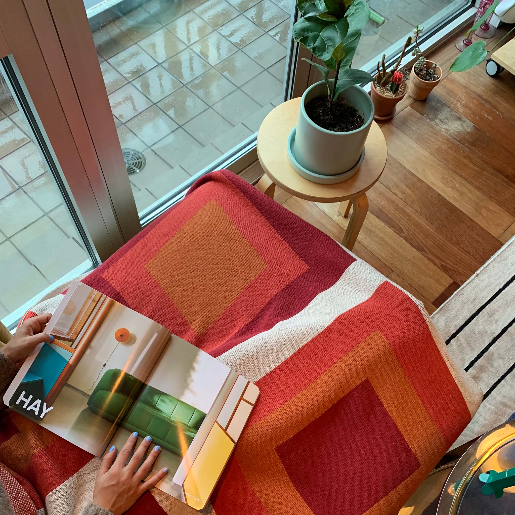 Person holding a magazine and using a red Bauhaus inspired blanket.