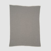 The Broken Zig Zag Throw Blanket, made from recycled cotton yarns and featuring a black and white chevron pattern, is shown flat on a white background.