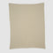 The Checkerboard Throw Blanket is a beige, rectangular knit with a subtle textured pattern and white trim, crafted from sustainable upcycled cotton—perfect for adding cozy style to any space. Shown flat on a plain white background.