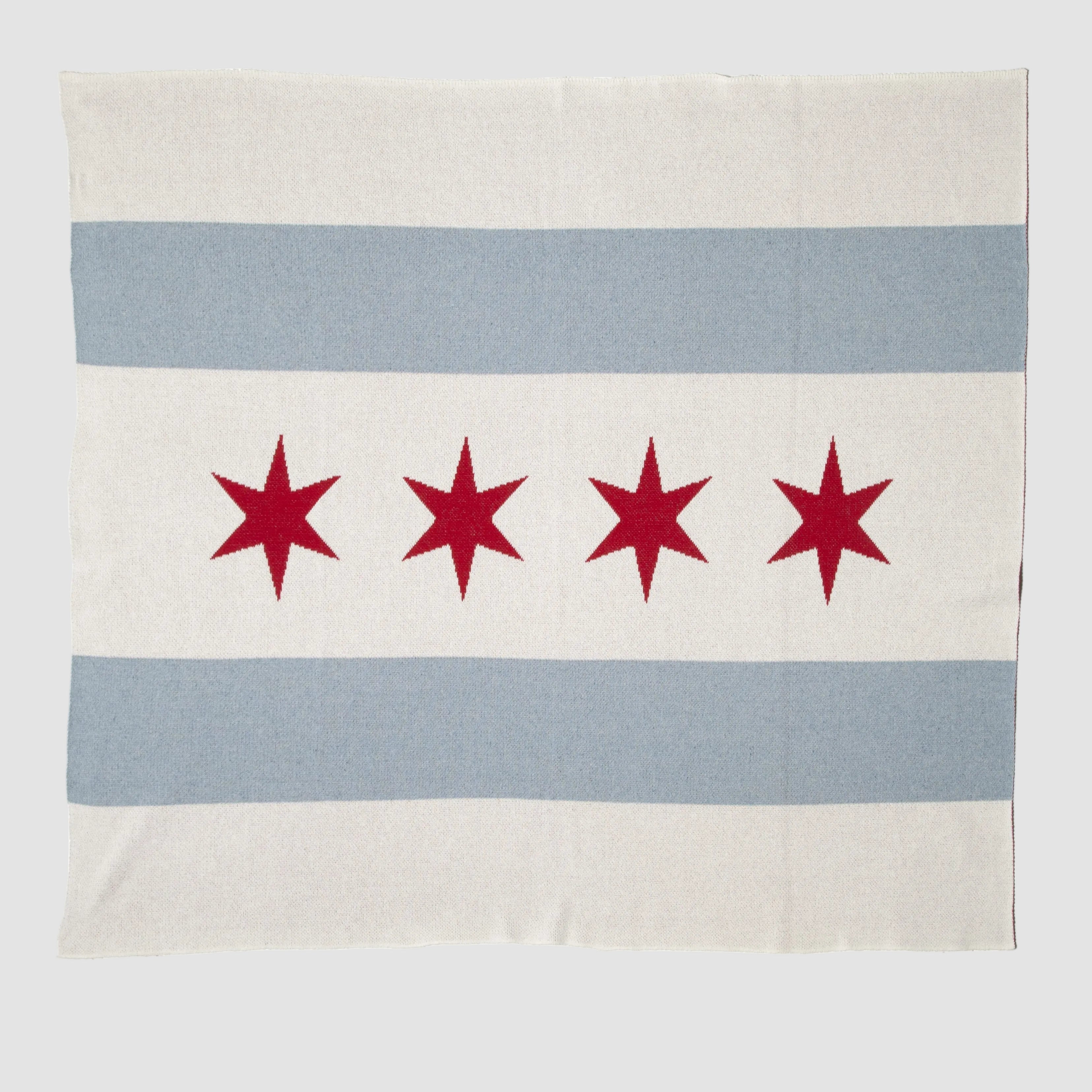 The Hometown Pride Flag - Cotton Sustainable Knit Blanket by in2green is a rectangular recycled cotton blanket, made in the USA, featuring two light blue horizontal stripes and four red six-pointed stars on a white background.
