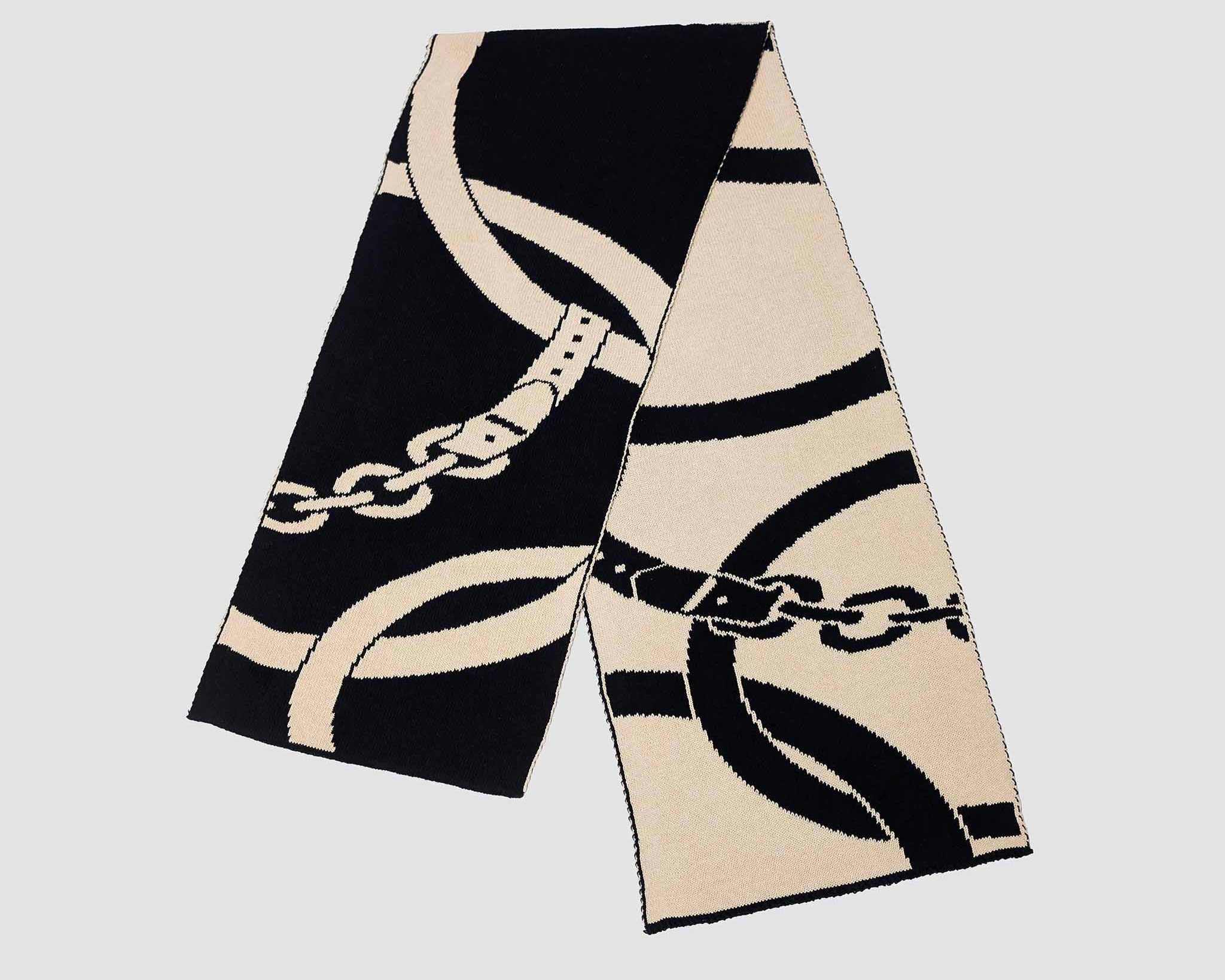 The Equestrian Loops Scarf by in2green is a long, rectangular sustainable cotton scarf with a black and beige abstract chain pattern on a plain background.