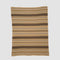 The in2green Geometric Stripe Throw Blanket is crafted from recycled cotton and features brown, tan, and cream horizontal stripes with geometric patterns—an eco-friendly accent for any room.