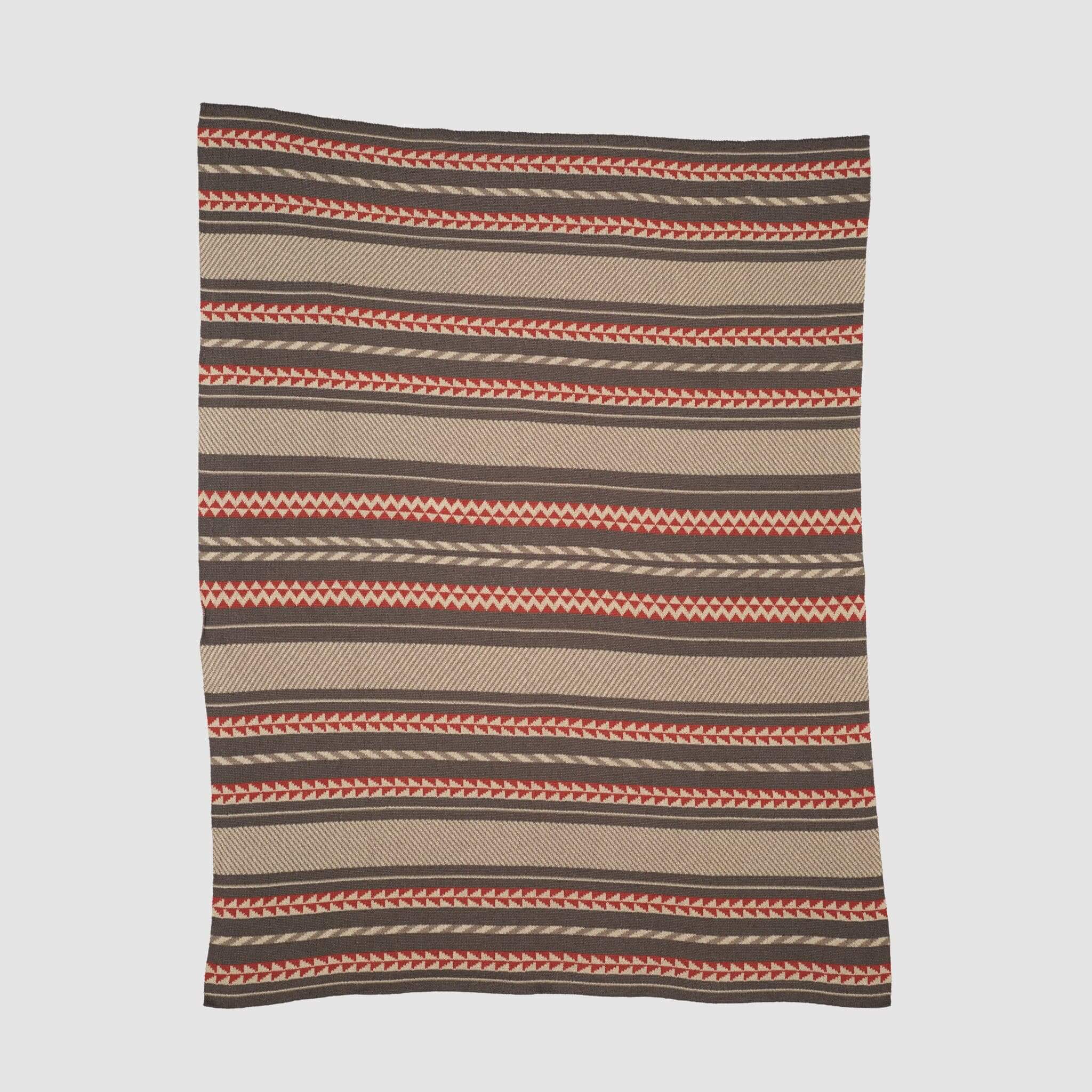 The in2green Geometric Stripe Throw Blanket is crafted from recycled cotton and showcases horizontal brown, tan, and orange patterns. This eco-friendly throw is displayed flat against a plain background.